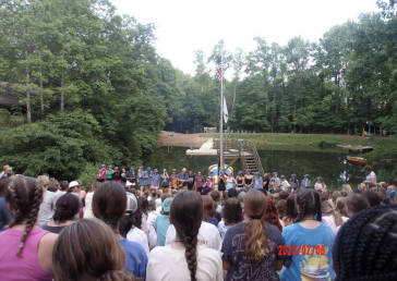 Campers gather for a campfire night at Camp Crestridge, sharing songs and time together by the lake. 